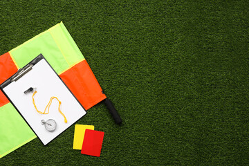 Different referee equipment on green grass, flat lay. Space for text