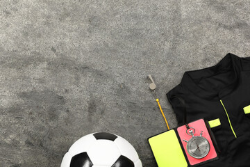 Referee jersey, soccer ball and other equipment on grey table, top view. Space for text