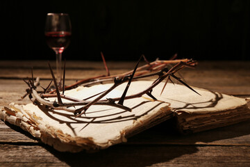 Crown of thorns and Bible on wooden table, closeup