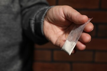 Drug addiction. Man with plastic bag of cocaine on blurred background, closeup