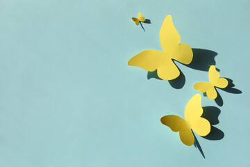 Yellow paper butterflies on turquoise background, top view. Space for text