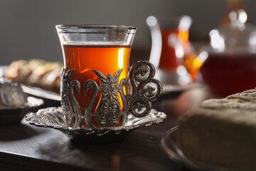 Glass of traditional Turkish tea in vintage holder on wooden table, closeup