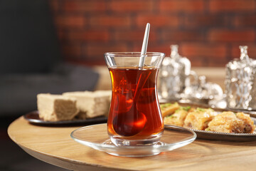 Traditional Turkish tea in glass and Eastern sweets on wooden table
