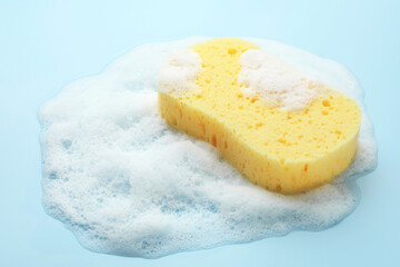 Yellow sponge with foam on light blue background