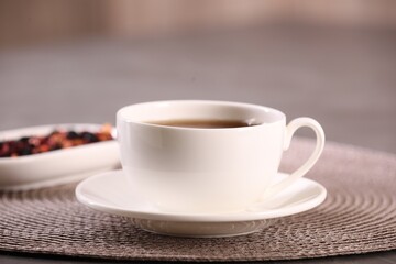Aromatic tea in cup and saucer on table, closeup