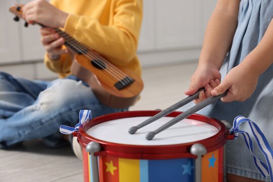 Little children playing toy musical instruments indoors, closeup