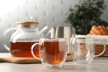 Aromatic tea in glass cup and teapot on light grey table