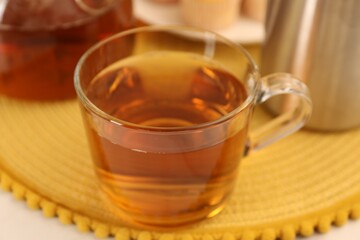 Aromatic tea in glass cup on table, closeup