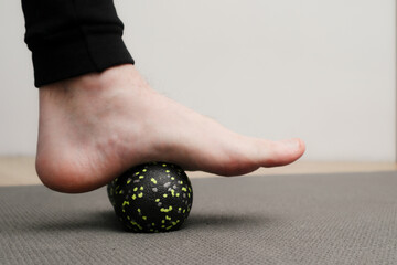 Foot massage with a ball. Concept of MFR, self-massage and physiotherapy. Myofascial release, relief of muscle pain.
