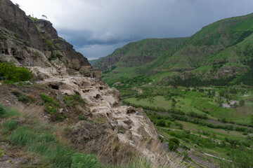 Fototapeta na wymiar Day view of the caves in the mountain, river valley and blue sky. Vardzia is a cave monastery, an ancient rock-hewn town, was excavated in the Erusheti Mountain.