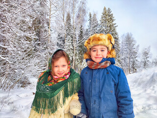 Two cute happy little cheerful children in winter snow forest. Photo shoot in stylized clothes of...