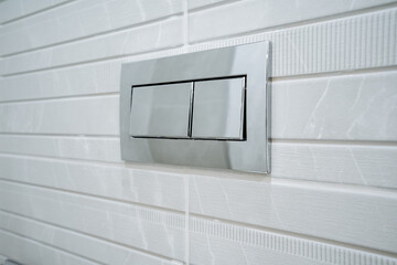 Rectangular silver flush plate with two buttons for concealed cistern on white tiles background