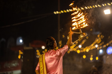 Ganga aarti, Portrait of young priest performing holy river ganges evening aarti at dashashwamedh ghat in traditional dress with hindu rituals. - obrazy, fototapety, plakaty