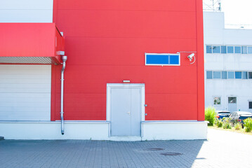 the red wall of the building with a door and a surveillance camera
