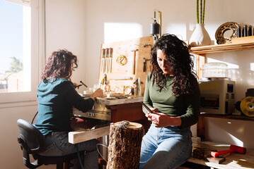 Female jewelers working in modern workshop together - obrazy, fototapety, plakaty
