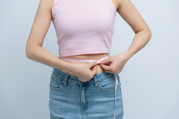 Cropped young woman in white clothes show loose pants after weightloss hold measure tape on waist