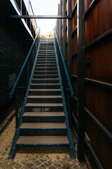 Metal Staircase in Urban Alleyway. Looking up a metal staircase between dark walls, an urban escape...