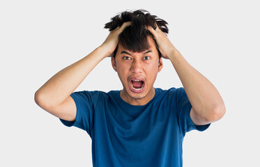 Young Asian man in blue t-shirt who is angry holding his head with his hands isolated on gray background.
