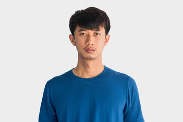 Fototapeta premium A young Asian man in his 20s wearing blue t-shirt is depressed and worried in distress standing on a gray background. Crying in anger and fear. Sad expression concept.