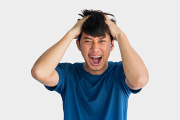 Young Asian man in blue t-shirt who is angry holding his head with his hands isolated on gray background.