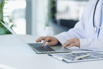 Asian female doctor working with laptop and health personal data in modern clinic, Healthcare and...