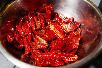 Sun-Dried Tomatoes Glistening in Metal Bowl. Close-up of glistening sun-dried tomatoes in a...