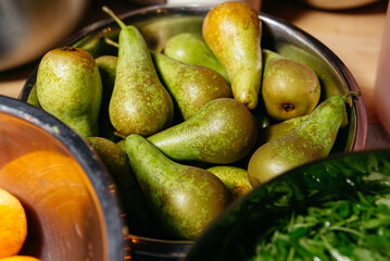 Bowl of Fresh Green Pears on Kitchen Counter. A stainless steel bowl overflowing with ripe green...