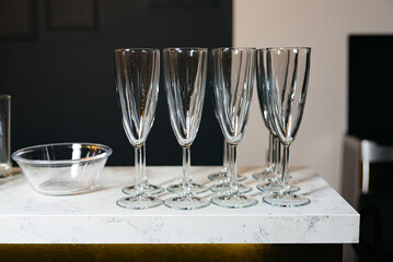 Elegant Empty Champagne Flutes on Marble Counter. A set of pristine champagne flutes arranged neatly on a modern marble countertop, reflecting sophistication and readiness for a celebration.