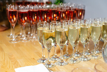 Sparkling White and Rosé Wine Ready for Toasting. Rows of sparkling white and rosé wine glasses on a wooden table, awaiting guests for a celebratory toast at a social event.