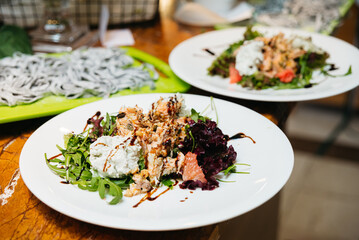Nicoise Salad with Tuna and Grapefruit on Plate. A Nicoise salad adorned with flaked tuna, grapefruit, and a balsamic glaze, presented on a white plate alongside pasta, ready to be enjoyed.