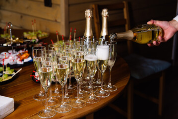 Champagne Pouring into Glasses for Celebration. A hand pouring champagne into elegant flutes...