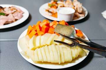 Freshly Sliced Melon and Papaya on Serving Platters. Sliced ripe melon and vibrant papaya presented on white platters, ready to be served as a refreshing fruit course.