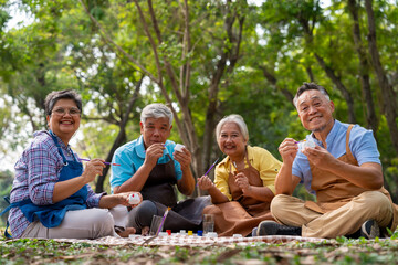 A group of Asian senior people enjoy painting cactus pots and recreational activity or therapy outdoors together  at an elderly healthcare center, Lifestyle concepts about seniority