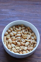 Roasted and salted Peanuts in a white bowl, also called groundnut, Shengdane, mungfali, and goober. Popular party snack. Copy Space. 