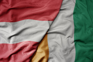 Obraz premium big waving national colorful flag of cote divoire and national flag of austria .