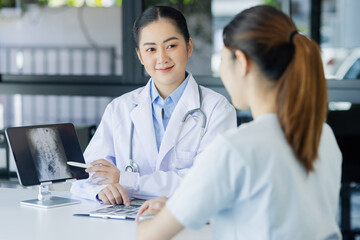 Asian female doctor explain to patient and looking at xrays indoors office, healthcare and medical...
