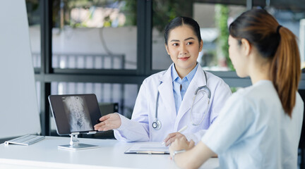 Asian female doctor explain to patient and looking at xrays indoors office, healthcare and medical concept.