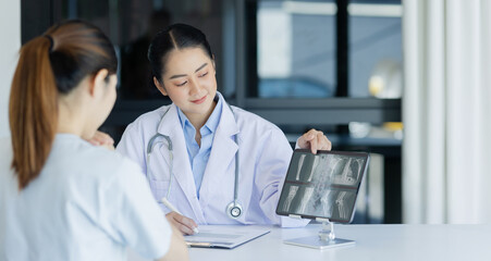 Asian female doctor explain to patient and looking at xrays indoors office, healthcare and medical...