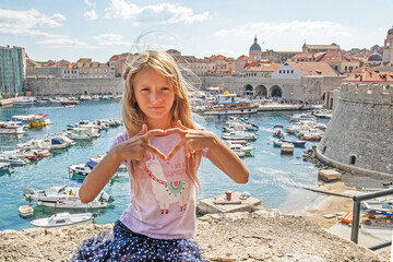 girl with long hair against the backdrop of the port in Dubrovnik in Croatia with a heart. euro-trip