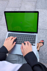 Female hands typing on laptop keyboard with green screen