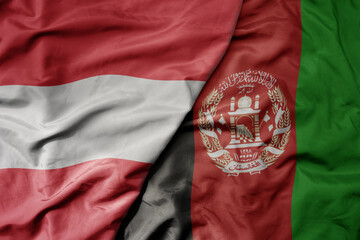 big waving national colorful flag of afghanistan and national flag of austria .