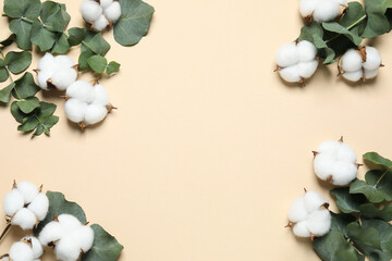 Naklejka na ściany i meble Cotton flowers and eucalyptus leaves on beige background, flat lay. Space for text