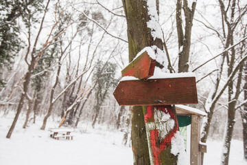 A wooden sign for a hiking trail on a snowy winter day.