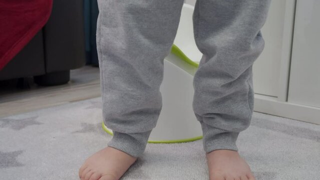 bare feet of child little boy sitting on a potty closeup