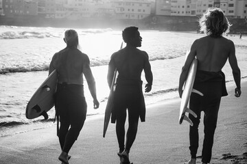 Multi generational surfer men having walking on the beach before surf session - Multiracial people,...