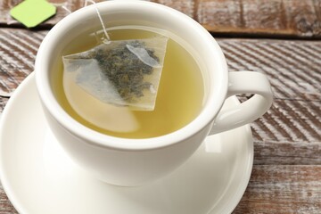 Tea bag in cup with hot drink on wooden rustic table, closeup
