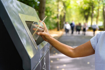 Close-up of woman hand putting a plastic container for recycling into a bin in a central Dublin park