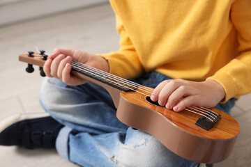 Fototapeta premium Little boy playing toy guitar indoors, closeup