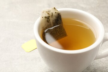 Brewing tea. Cup with tea bag on light table, closeup. Space for text