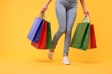 Woman with shopping bags on yellow background, closeup